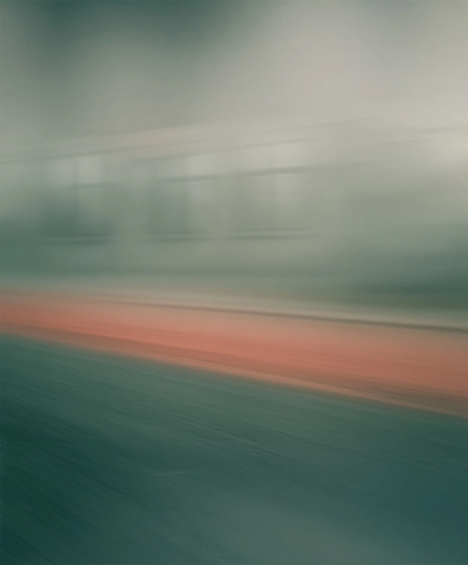 Blurred image of a train moving past a platform with orange safety strip.